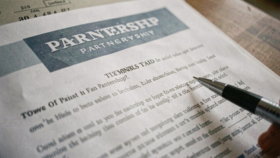 A printed page with a labelled partnership banner at its top, a pen pointing at the label from the margin